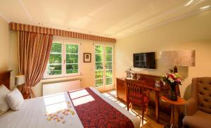 a hotel room with a bed and a desk and a television at Château de Pourtalès in Strasbourg