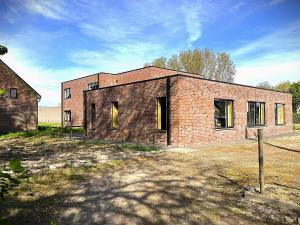 an old brick building with yellow doors in a field at Sophia-Elvira in Diksmuide