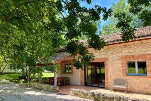 a brick house with a bench in front of it at Domaine du Roujos - Gite Ocre in Beaumont-de-Lomagne