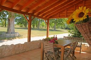 a wooden table and chairs under a wooden pergola at Domaine du Roujos - Gite Ocre in Beaumont-de-Lomagne