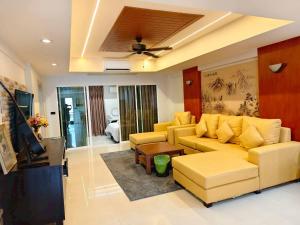 a living room with a yellow couch and a tv at 3-bedroom apartment, Patong, Palm Spring 602 in Patong Beach