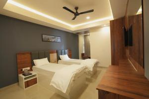 a bedroom with two beds and a ceiling fan at Hotel ASG Grand in Ranipet +9 photos