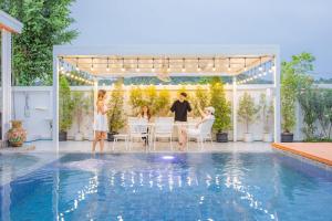 a group of people sitting around a table by a pool at KN Pool Villa Saraburi in Ban Huai Sai (1)