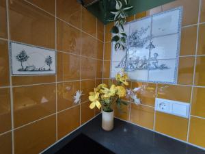 a yellow tiled bathroom with a vase of flowers on a counter at Morgenstond in Groesbeek