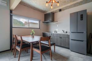 a kitchen with a table and chairs and a refrigerator at Rusutsu Backcountry Lodge in Kimobetsu