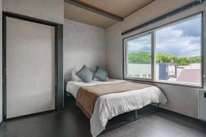 a bedroom with a bed and a large window at Rusutsu Backcountry Lodge in Kimobetsu
