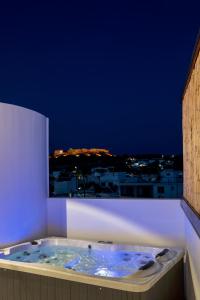 a jacuzzi tub with a view of a city at night at ARCH Luxury Suites in Archangelos