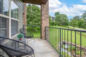 a porch with two chairs and a fence at Couples Condo Retreat Overlooking Golf Course in Branson West