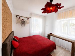a bedroom with a red bed with a red blanket at Oāze Aucē in Auce