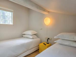 a bedroom with two beds and a lamp on a table at Hôtel L'orque Bleue in Sète