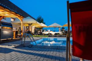 ein Pool mit Rutsche, Tischen und Sonnenschirmen in der Unterkunft Hotel Rozkoš in Česká Skalice