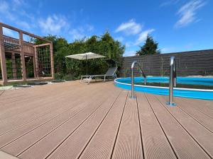 a deck with a swimming pool and an umbrella at Apartamenty przy Skwerku in Sztutowo