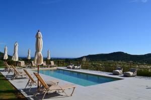 a swimming pool with lounge chairs and umbrellas at Wild Cretan West in Drakiana