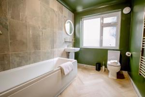 a bathroom with a tub and a toilet and a window at The Whitehouse - Flat B in Carbis Bay