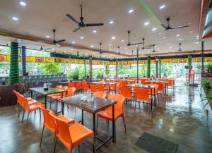 a restaurant with orange chairs and tables and windows at Treebo Sunshine Beach Resort with Swimming Pool in Calangute