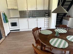 a kitchen with a wooden table with chairs and a kitchen with white cabinets at Small house in rural surroundings in Gelstrup