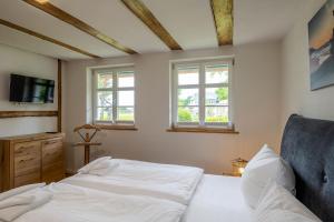 a bedroom with a bed and a tv and two windows at Haus Tadder in Born