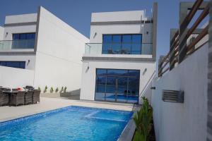 a house with a swimming pool in front of it at Al Dana H2O Beachfront Villa with a private pool, Al Dana Island Sharm Fujairah in Sharm