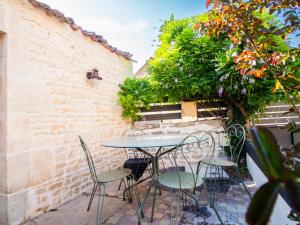 a patio with a table and chairs on a brick wall at L'Ecrin des Roches in Le Langon