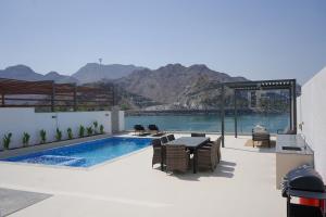 a patio with a pool and a table and chairs at Al Dana H2O Beachfront Villa with a private pool, Al Dana Island Sharm Fujairah in Sharm