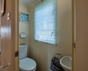 a bathroom with a toilet and a sink and a window at Finest Retreats - Seascape in Porchfield +19 photos