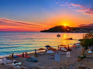 a beach with chairs and umbrellas at sunset at Prinnos Rooms Himare in Himare