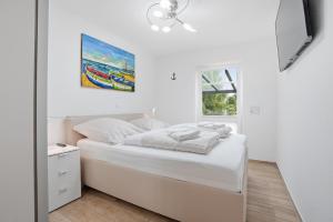 a white bedroom with a bed and a mirror at Grachtenblick I in Greetsiel