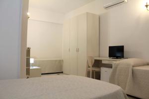 a bedroom with two beds and a desk with a television at Villa Bice in Pulsano