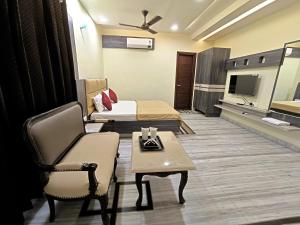 a room with two beds and a chair and a table at Hotel Sunshine Apartment in Bathinda