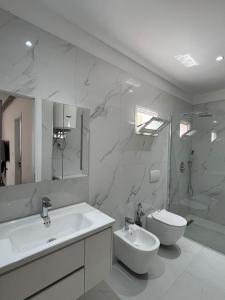 a white bathroom with a sink and a toilet at Golden Stay in Pogradec +9 photos