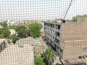 a view of a building from behind a wire at Hotel Sunshine Apartment in Bathinda