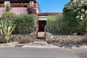 a house with a gate and a stone wall at Bilo Lu Impostu in Nuragheddu