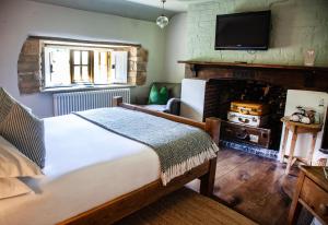 a bedroom with a bed with a fireplace and a television at The Ebrington Arms in Chipping Campden