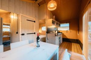 a kitchen with a white table with a bottle of wine at Safari Lodges in Nieuwe Wetering
