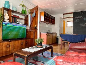 a living room with a flat screen tv and a table at Zoete Inval Travelers Lodge-Backpacker Loft in Hermanus