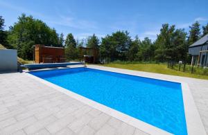 a swimming pool in a yard next to a house at Domek Reset Kaszuby - Basen, Jacuzzi, Sauna, Siłownia in Łączyno