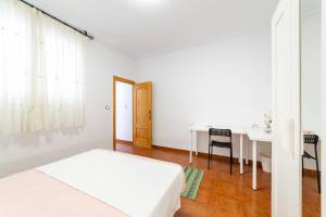 a white bedroom with a bed and a table at Casa Maruchi Apartamento 2 in Almería