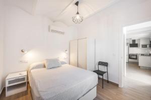 a white bedroom with a bed and a chair at Casa Socra in Arcos de la Frontera