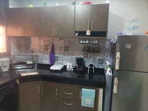 a kitchen with a black counter top and a refrigerator at Tajhiz alliance darna in Kenitra +3 photos