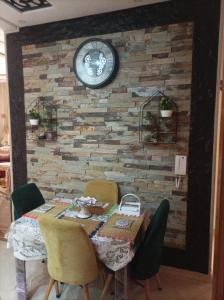 a dining room table with chairs and a clock on a wall at Tajhiz alliance darna in Kenitra