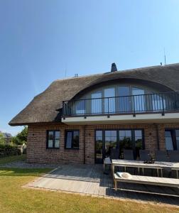 a large brick house with a deck and a balcony at SunCliff Lodge - exklusive private Sauna, Sanarium, Kamin und Meerblick in Dranske