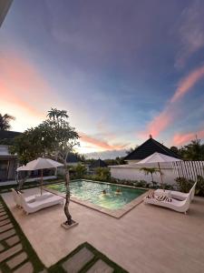 a pool with chairs and people swimming in it at Kelingking Green Village in batumadeg