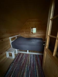 a bed in a wooden room with a door at Cabanele din RÂTUL FLORILOR in Hotar +16 photos