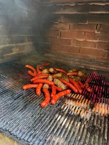 a bunch of hot dogs and meat on a grill at Cabanele din RÂTUL FLORILOR in Hotar