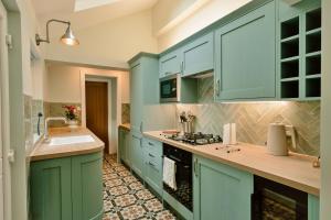 a kitchen with blue cabinets and a sink at Finest Retreats - 2 Haywood View in Grindleford Bridge