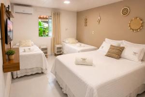 a hotel room with two beds and a television at Pousada da Gih in Fernando de Noronha