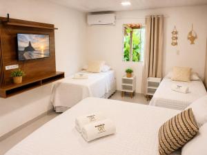 a hotel room with two beds and a television at Pousada da Gih in Fernando de Noronha