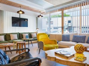 a living room with a couch and chairs and tables at ibis Styles Salon de Provence in Salon-de-Provence