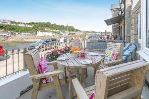 a table and chairs on a balcony with a view of the water at 3 Bed in Porthleven oc-1seav in Porthleven