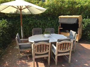 a table and chairs with an umbrella and a grill at Residenz Seelust in Langeoog
